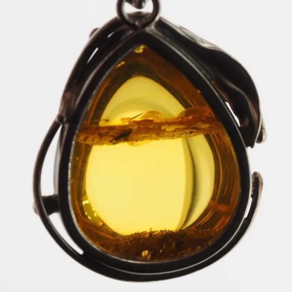 Przezroczysty bursztyn z szczątkami roślinnymi  i srebro oksydowane - wisiorek