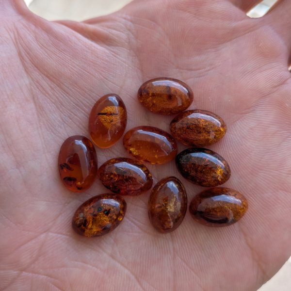 Bursztyn koniakowy z wewnętrznymi łuskami kaboszony owalne 15x10 mm – pakiet 10 szt.